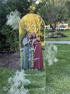 two women standing in front of a large mirror