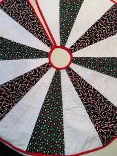 a close up of a quilted table topper on a white cloth with black and red designs