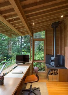 a room with a desk, chair and wood stove in the corner next to it