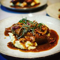 a white plate topped with mashed potatoes covered in gravy and garnish