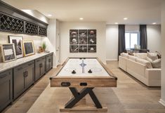 a living room filled with furniture and a pool table in the middle of the room