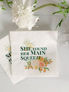 two napkins sitting on top of each other with flowers in front of them and the words, she found her main squeeze