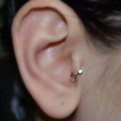 a close up view of a person's ear with a single pearl in the middle