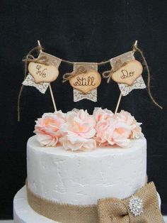 a wedding cake with two wooden hearts on top and flowers in the middle, sitting on a table