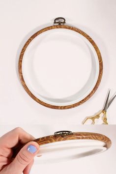 a hand holding scissors and a wooden ring