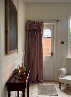 a living room with a white chair and a red striped drape on the window