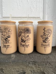 three jars with flowers on them sitting next to each other