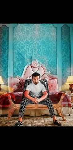 a man sitting on top of a wooden bench in front of a blue and red wall