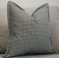 a black and white checkered pillow sitting on top of a couch next to pillows