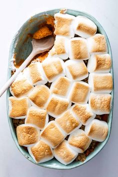 a bowl filled with marshmallows on top of a white table next to a spoon