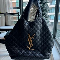 Luxurious Black Tote Bag Made Of Quilted Leather With A Distinctive Diamond-Shaped Pattern, Featuring A Prominent Gold-Toned Ysl Logo On The Front. Dimensions: 38/58 X 43 X 8 Cm / 15/22.8 X 16.9 X 3.1 Inches Handle Drop: 23 Cm / 9 Inches Can Be Worn Wide Or With Closed Sides Light Bronze-Toned Metal Hardware Detachable Metal Chain Toggle Closure Interior: One Removable Zipped Pouch Grosgrain Lining Includes Dust Bag Ysl Tote Bag, Ysl Tote, Saint Laurent Bags, Ysl Logo, Yves Saint Laurent Bags, Black Tote, Black Quilt, Diamond Shaped, Quilted Leather