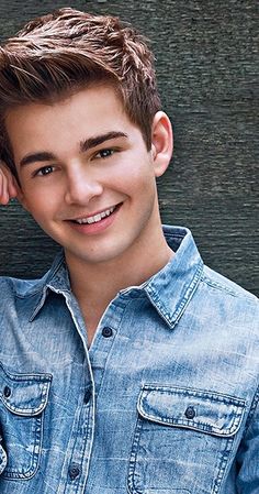 a young man wearing a denim shirt posing for a photo