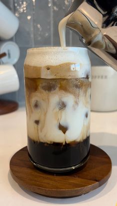 a glass filled with liquid sitting on top of a wooden coaster