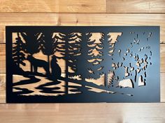 a metal cutout of trees and animals in the woods on a wooden wall with wood planks