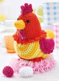 a crocheted chicken sitting on top of a pile of pink and yellow yarn