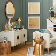 a living room with green walls and gold accents on the sideboard, white furniture, and framed pictures