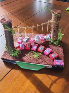 a wooden table topped with a green container filled with chocolates and tied in twine