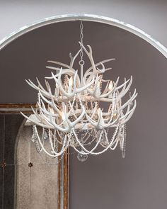 a chandelier hanging from the ceiling in a room with an arched doorway and mirror