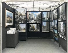 an exhibit booth with multiple pictures on it's walls and the floor is covered in gray carpeting