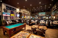 a room filled with lots of tables and chairs next to a pool table on top of a hard wood floor