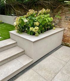 a planter filled with flowers sitting on the side of a set of concrete steps