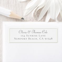 a close up of a white envelope with a pencil and flower on the table next to it