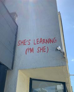 graffiti on the side of a building that says she's learning i'm she