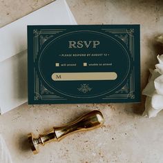 a wedding card with a gold seal on it next to a white envelope and flower