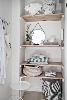 a white closet with shelves filled with clothes and other items on top of the shelves