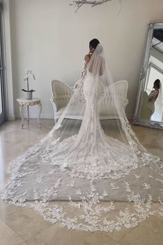 a woman in a wedding dress is standing near a mirror