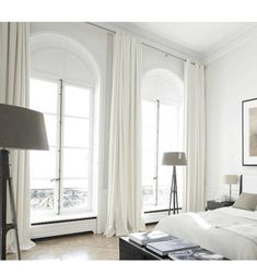 a bedroom with white walls and curtains on the windows