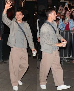 two men walking down the street with their arms in the air and one holding a can