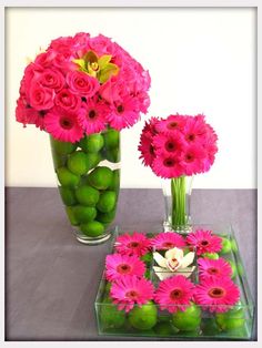 two vases filled with pink flowers and green apples sitting on top of a table