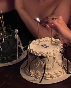 a woman is cutting into a cake with two candles on it and the man has his shirt off