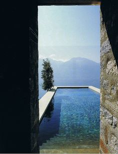 an open door leading to a pool with water and mountains in the backgroud