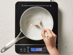 a person using a spoon to stir something in a saucepan on a stove top