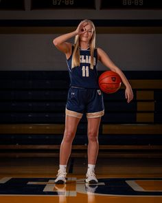 a female basketball player holding a ball in her hand and posing for the camera with both hands behind her head