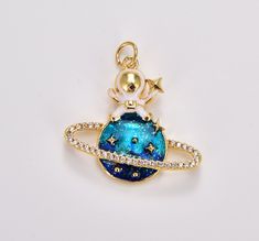 a gold plated charm with an image of the planet and stars on it's side