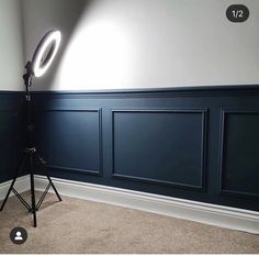 a tripod light sitting on top of a carpeted floor next to a wall