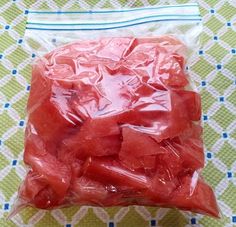 a plastic bag filled with pieces of watermelon on top of a tablecloth