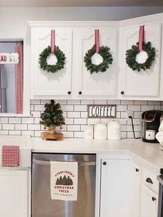 a kitchen decorated for christmas with wreaths hanging on the cabinets and dishwasher