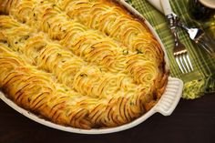 a casserole dish with pasta and cheese in it on a table next to utensils