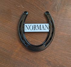 a black horseshoe with the word norman on it sitting on top of a wooden table