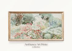 an art print hangs on the wall above a painting with flowers and trees in it