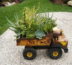 an old toy truck is filled with plants and succulents in the garden