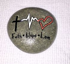 a rock with the word faith hope love painted on it and a heart in the center