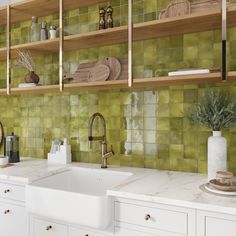 a kitchen with green tiles on the wall and wooden shelves over the sink, along with white cabinets