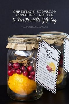 two mason jars filled with oranges, cranberries and christmas recipe tags sitting on top of a table