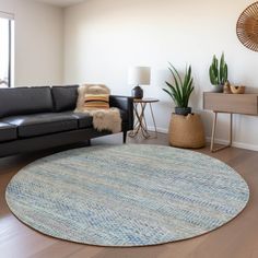 a living room with a black couch and a round rug on the floor in front of a window