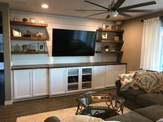 a living room filled with furniture and a flat screen tv mounted on the wall above it